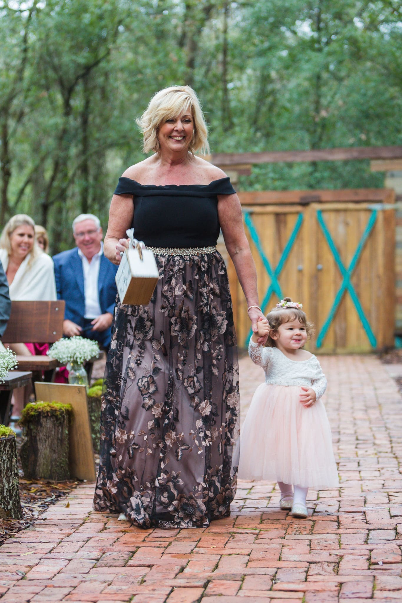 Mother of the bride walking down the aisle with the bride and groom's daughter and flower girl.