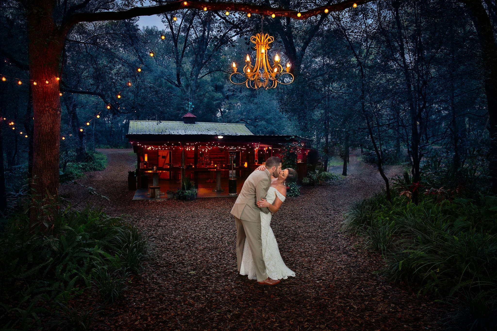 Bride and groom kissing under the chandelier at Bridle Oaks.