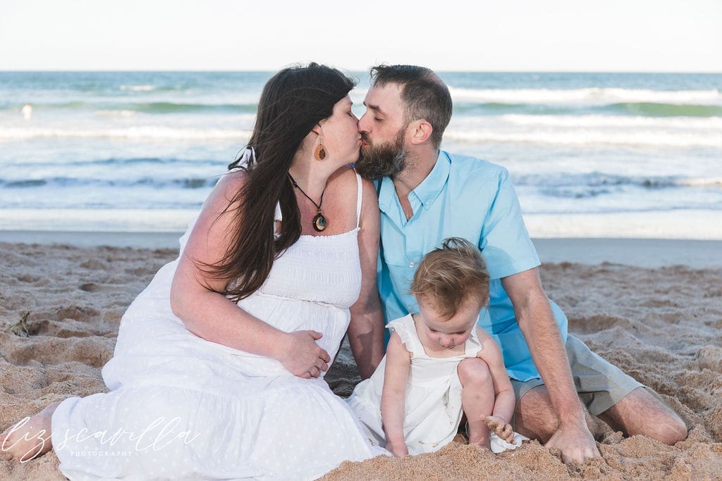 Family maternity session on the beach with expecting mother, partner, and child in Ormond Beach, Florida