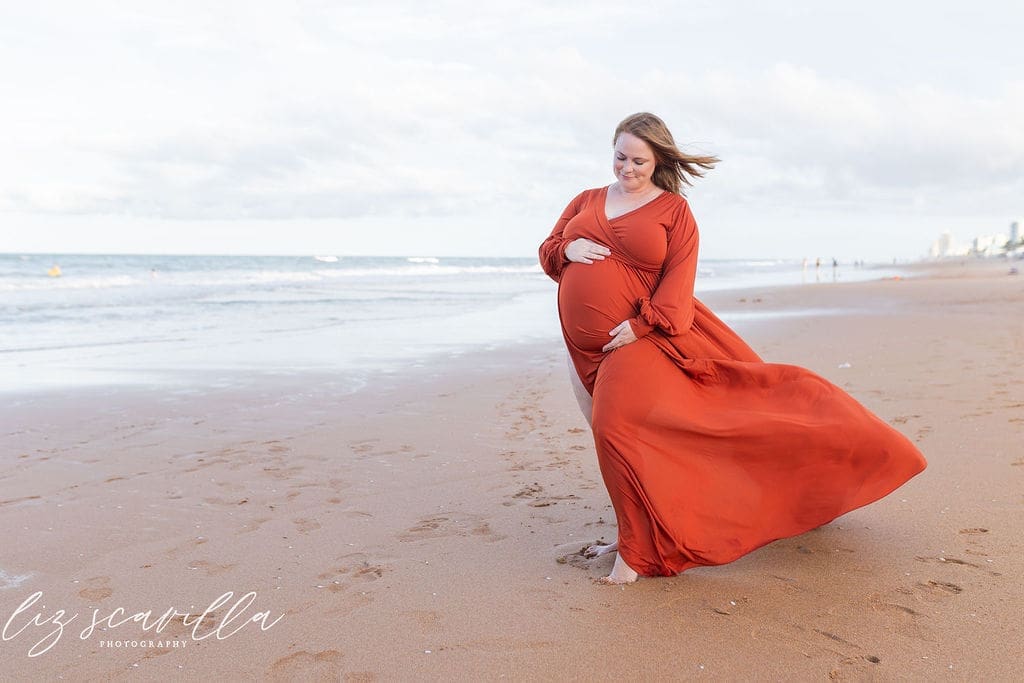 Pregnant mother in a flowing dress during a beach maternity photography session in Ormond Beach, Florida